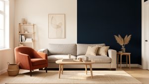 Salon lumineux et chaleureux avec murs blanc cassé, canapé greige, fauteuil terracotta et mur d’accent bleu nuit, éclairé par une lumière naturelle latérale.