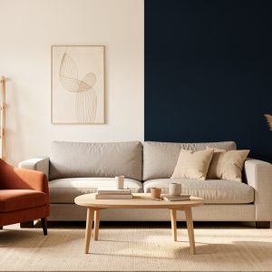 Salon lumineux et chaleureux avec murs blanc cassé, canapé greige, fauteuil terracotta et mur d’accent bleu nuit, éclairé par une lumière naturelle latérale.